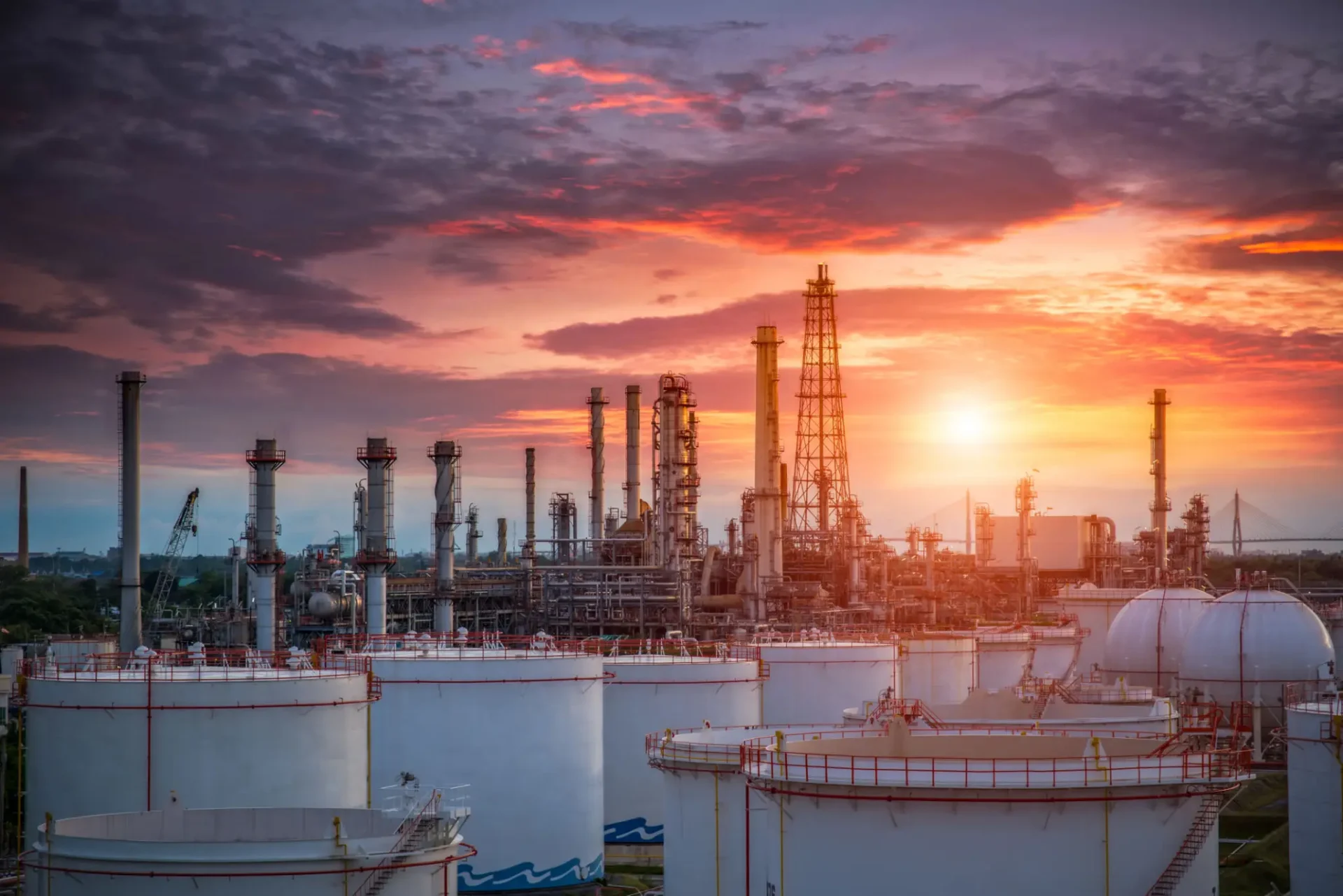 Oil refinery at sunset with storage tanks.