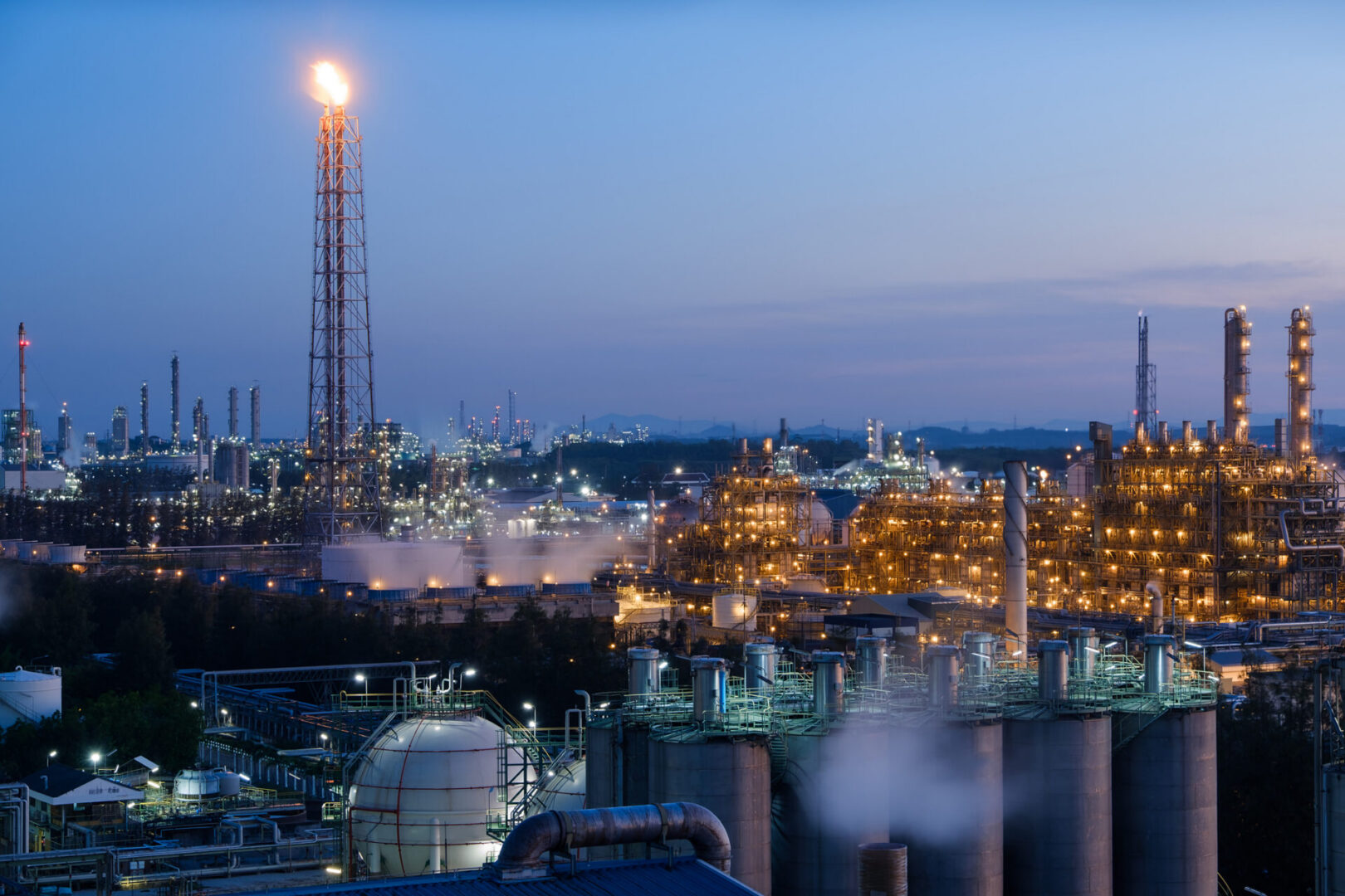 Industrial refinery complex at dusk with lights.